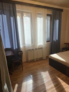 a bedroom with a bed and a desk and windows at House 56 in Yerevan