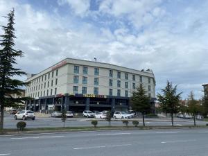 a large white building with cars parked in a parking lot at BUSINESS EXPRESS HOTEL in Kapaklı