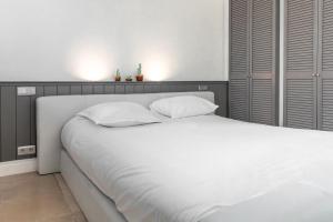 a white bed with white sheets and pillows at Esplanada Studios in Genk