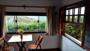 a table and chairs in a room with two windows at Pousada Vila do Campo in Lavras Novas