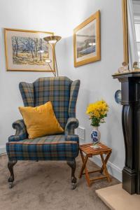 a blue chair with a yellow pillow next to a table at Fisherman's Cottage in Cockenzie