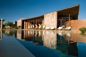 a building with chairs and a pool of water at Tierra Atacama in San Pedro de Atacama