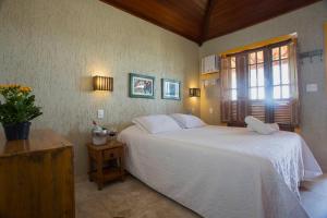 Un dormitorio con una gran cama blanca y una ventana en Bliss Hotéis Concept, en Búzios