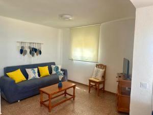 a living room with a blue couch and a table at Apartamento con vistas al mar! Comaruga in La Playa
