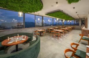 a restaurant with tables and chairs and large windows at Boulevard Premium Luxury Hotel in Munnar