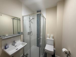a white bathroom with a shower and a sink at Magna House in Egham