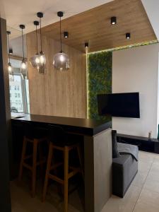 a kitchen with a bar with chairs and a tv at ALEKSANDRA 5 - Leaf in Kielce