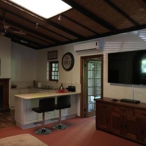 a kitchen with two bar stools and a flat screen tv at Kentia Palms in Old Reynella