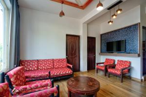 a living room with red furniture and a flat screen tv at Baga Riverview 2BHK Mayonna Apartment in Baga