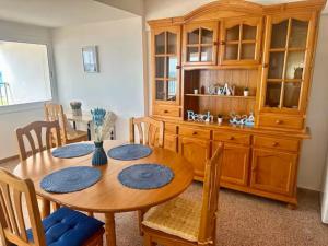 a dining room table with chairs and a wooden hutch at Apartamento con vistas al mar! Comaruga in La Playa