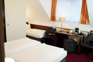 a hotel room with two beds and a desk and chairs at Haus Sparkuhl Hotel Garni in Hannover