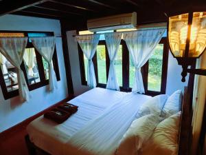 a bedroom with a white bed with windows at Huen Tip Viman Chiangmai in Ban Nong Ho