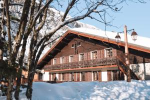 a large wooden building with snow on the ground at Hotel Le Genepy in Tignes +4 photos
