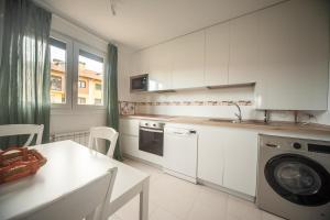 a kitchen with white cabinets and a table and a washing machine at La Casa del Columpio, Comillas in Comillas