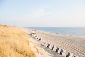 a beach with blue chairs and the ocean at Rantum Lodge in Rantum