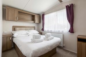 a bedroom with a bed with towels on it at Hotel du Van - Rockley Park Caravan, Activities On-site in Poole