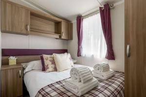 a bedroom with a bed with two towels on it at Hotel du Van - Rockley Park Caravan, Activities On-site in Poole