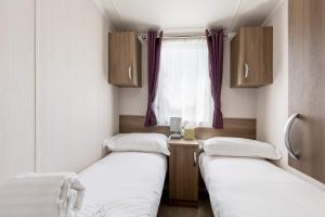 two beds in a small room with a window at Hotel du Van - Rockley Park Caravan, Activities On-site in Poole +20 photos