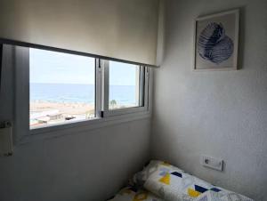 a bedroom with a window with a view of the beach at Apartamento con vistas al mar! Comaruga in La Playa