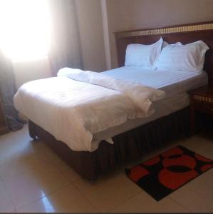 a large bed with white sheets and pillows on it at Sefitel in Lubumbashi +9 photos