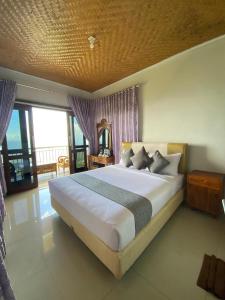 a bedroom with a large bed and a balcony at De La Sierra in Munduk