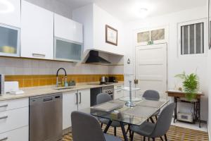 a kitchen with white cabinets and a glass table and chairs at Rochinha Cozy Home in Funchal