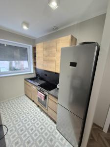 a kitchen with a stainless steel refrigerator and wooden cabinets at Apartament Mickiewicza 3 in Września