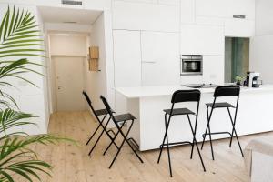 a kitchen with black chairs and a white counter at STUDIO 14 - apt design con terrazza sul fiume - 2 biciclette incluse - vicino al centro in Treviso