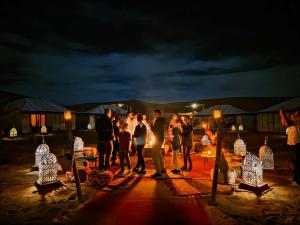 a group of people standing on a beach at night at Sinbad Merzouga Camp in Merzouga