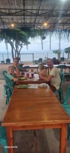 a group of people sitting at a table at the beach at BougenVille in Labu Pumi
