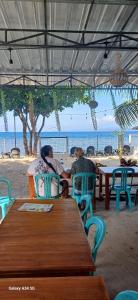two people sitting at a table on the beach at BougenVille in Labu Pumi