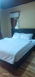a bed with white sheets and pillows in a bedroom at BougenVille in Labu Pumi