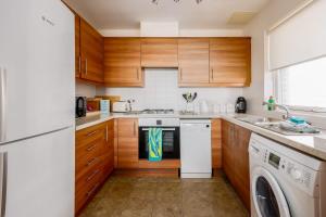 a kitchen with wooden cabinets and a washer and dryer at Island's Edge- Moments from Hamworthy Beach and Park in Poole