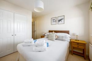 a bedroom with a large white bed with towels on it at Island's Edge- Moments from Hamworthy Beach and Park in Poole +29 photos