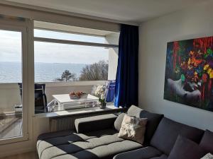 a living room with a couch and a large window at Meerblick 1 in Sierksdorf