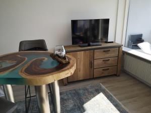 a living room with a table and a tv at Meerblick 1 in Sierksdorf