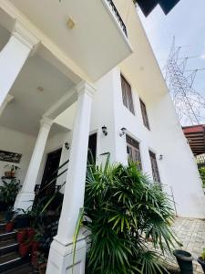 a white house with plants in front of it at Akshi Hostel in Kandy