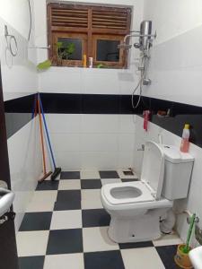 a bathroom with a toilet and a checkered floor at Akshi Hostel in Kandy