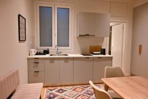 a kitchen with white cabinets and a table and a table and chairs at Brand New! Fresh Kolonaki Studio in Athens