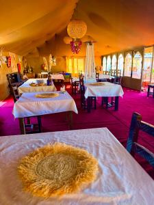 a dining room with tables with white tablecloths at Sinbad Merzouga Camp in Merzouga +58 photos