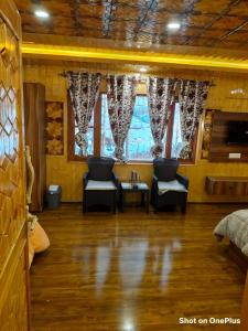 a room with two chairs and a table and windows at Hotel Pahalgam view in Pahalgām