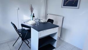 a black and white desk with two chairs and a bottle of wine at Logement - maison d'hôtes Communay in Communay
