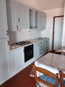 a kitchen with white cabinets and a table at Residence Costa Caddu San Teodoro in Porto Ottiolu