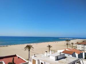 a view of a beach with palm trees and buildings at Apartamento con vistas al mar! Comaruga in La Playa