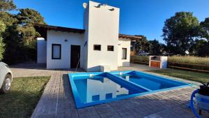 a blue swimming pool in front of a house at Duplex La Caleta Mar in Mar de Cobo