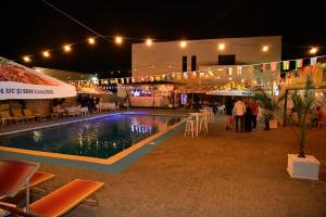 a swimming pool at night with people standing around it at Pensiunea Ada in Balta Verde