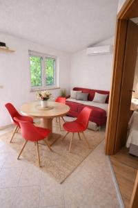 a living room with a table and red chairs at Perla Mare in Sumartin