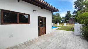 a white house with a wooden door and a yard at Duplex La Caleta Mar in Mar de Cobo
