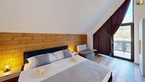 a bedroom with a large white bed with a wooden wall at Chalet pod Skalou in Liptovská Anna