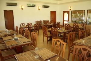 an empty restaurant with wooden tables and chairs at Manor Backwater Resort in Kumarakom